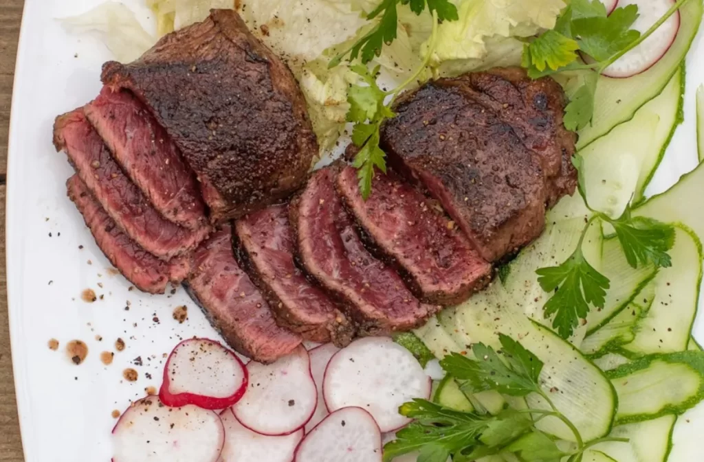 Sliced beef steak with fresh salad on a white plate