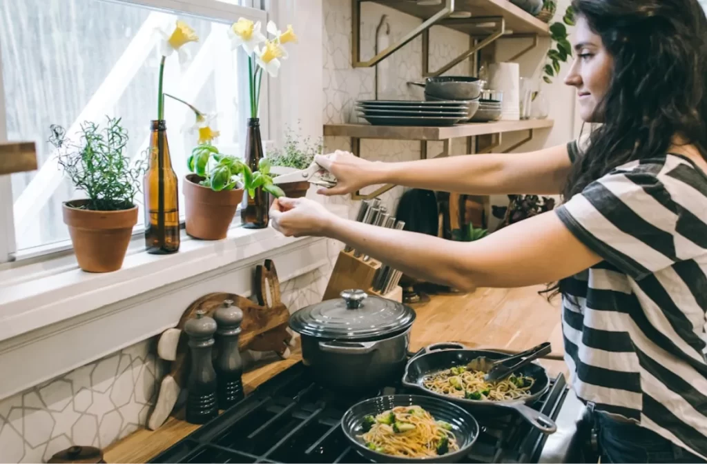 Woman picking fresh herbs in a cozy kitchen.