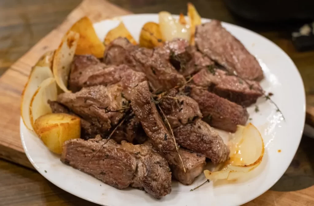 Cooked beef pieces with potatoes and onions on a plate