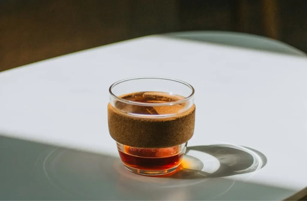 Small glass cup with coffee in bright sunlight – shop coffee tables on sale.
