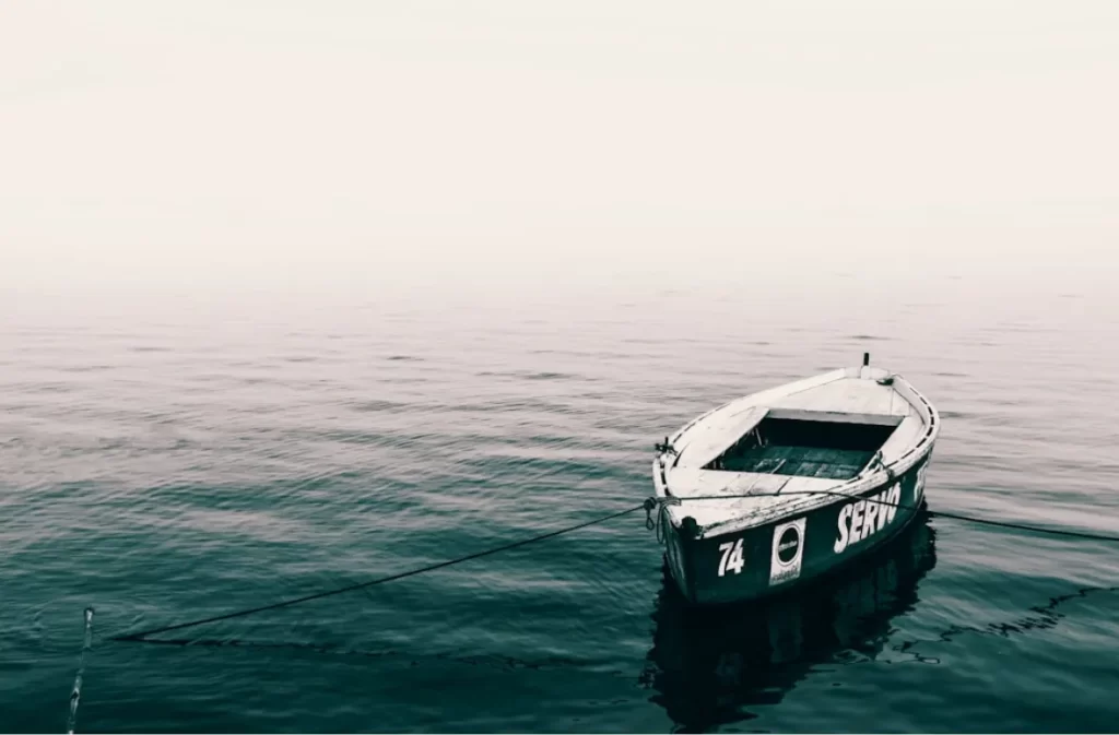 A small, solitary boat floating on a calm sea.