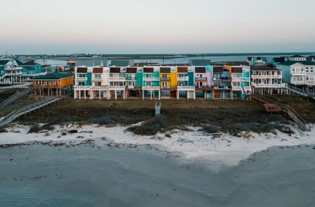 Vibrant beachfront houses on raised stilts by the shore.