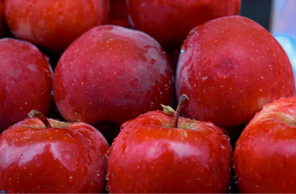 A close-up of shiny red apples with water droplets.