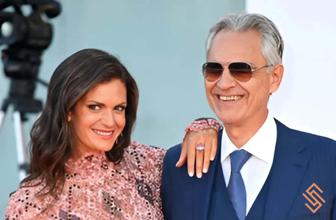 Andrea Bocelli and a woman posing at an outdoor event in formal wear.