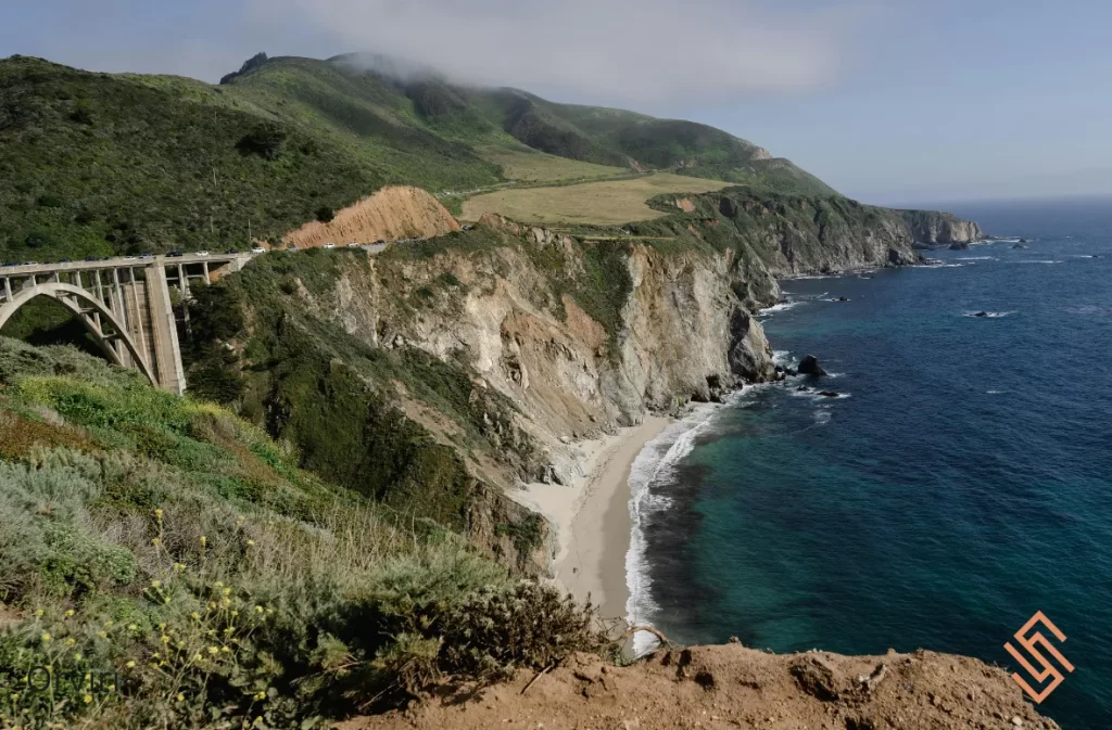 A scenic coastal cliff with a bridge overlooking the ocean.