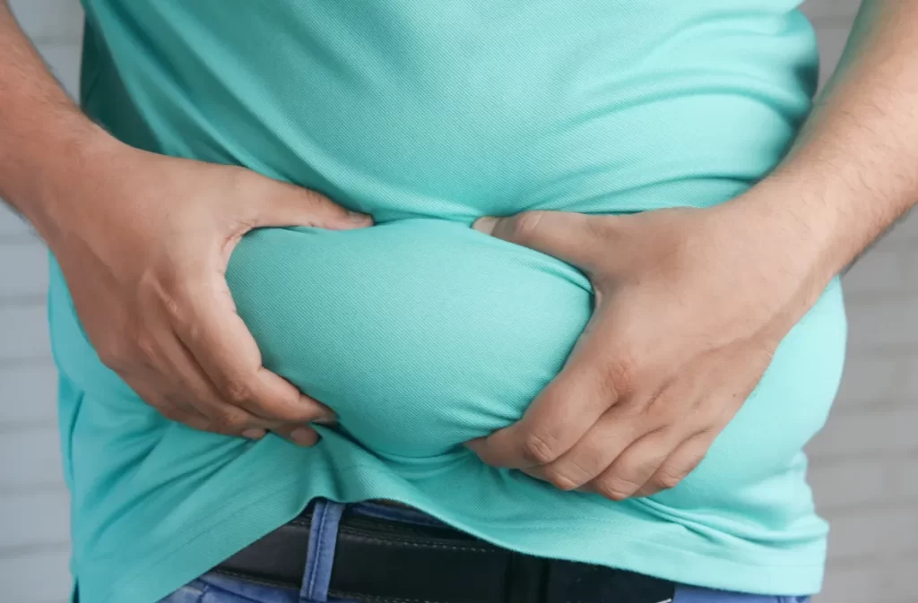 Person holding excess belly fat with both hands