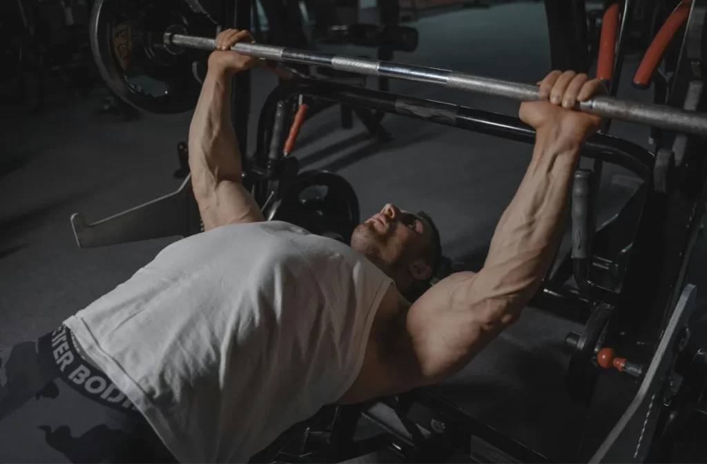 Man bench pressing heavy weights in a dimly lit gym