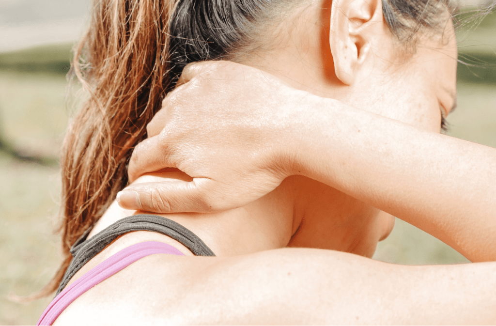 Woman holding her neck outdoors, stretching for relief.