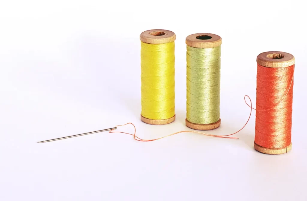 Three colorful spools with threaded needle