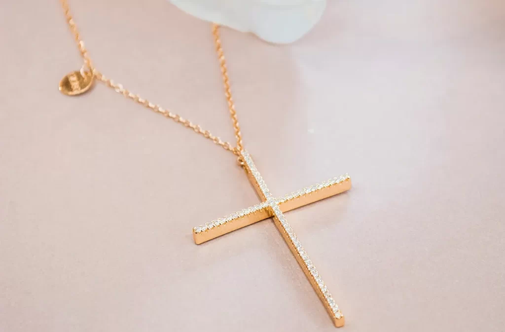 A golden cross necklace with diamonds on a soft background.