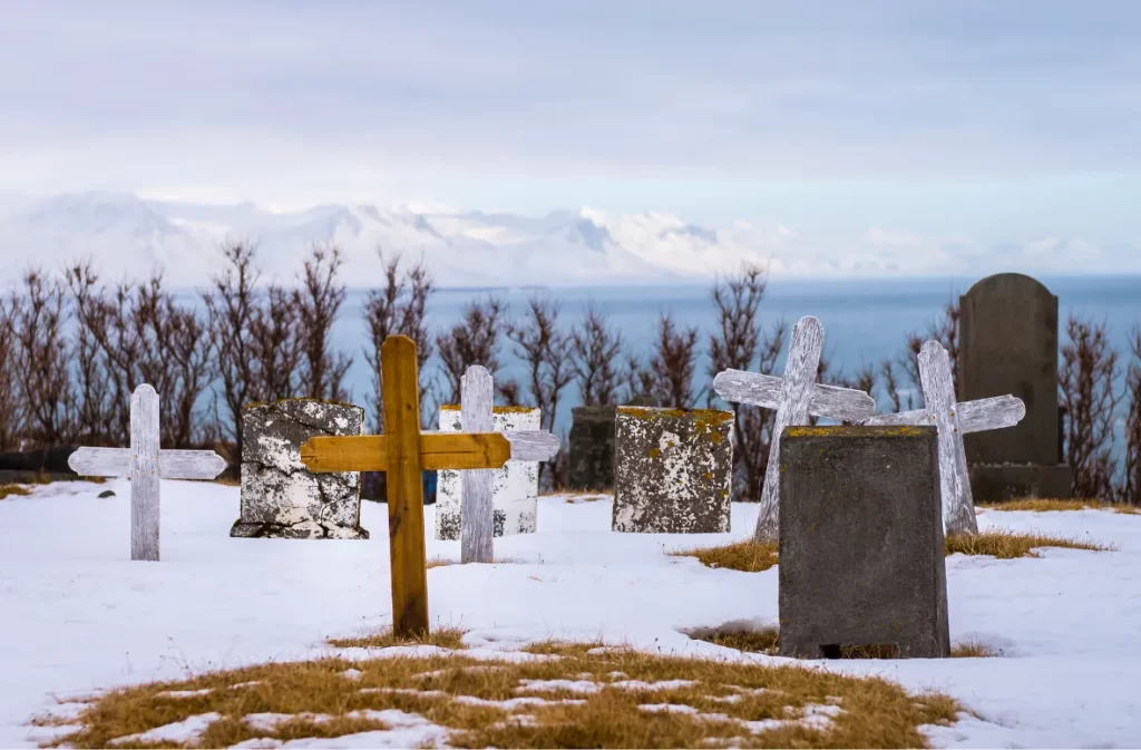 Snow-covered graves with wooden and stone crosses.